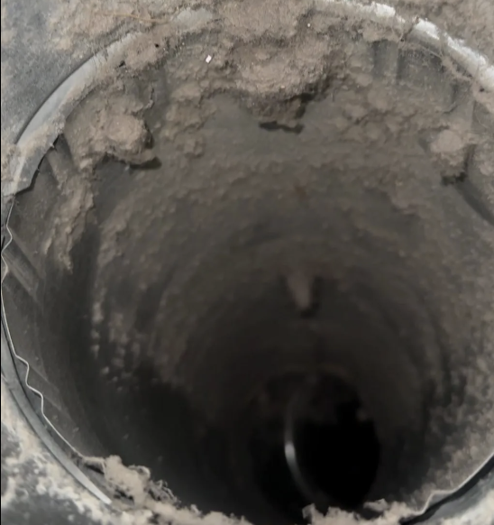 Dirty round duct caked with debris before cleaning